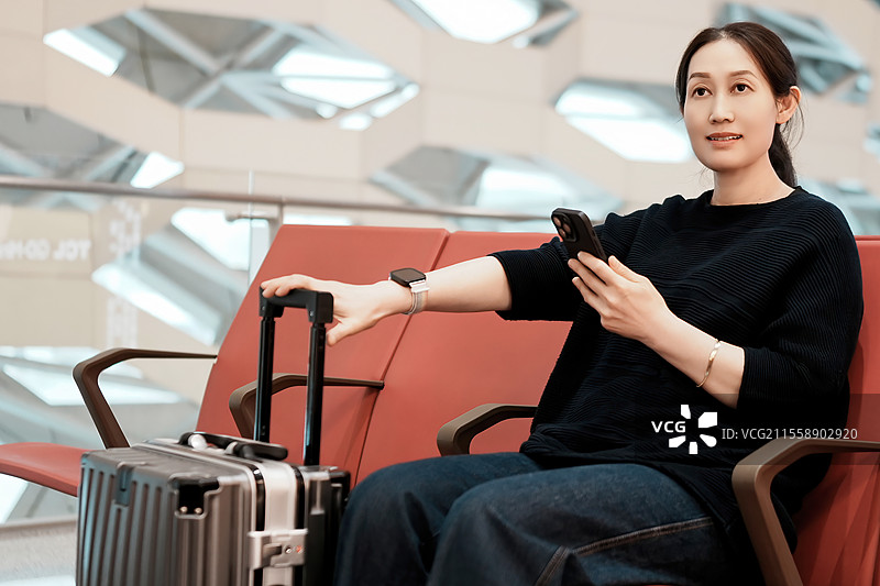 女人在机场放松与手提箱和智能手机图片素材
