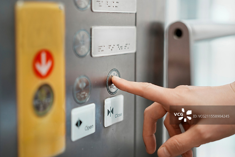 现代建筑环境中的手按电梯按钮图片素材