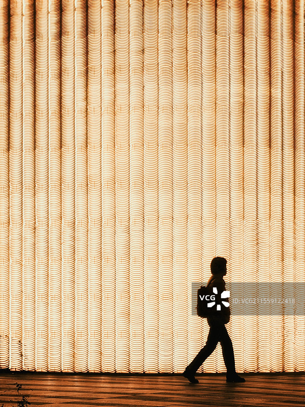 夜归~夜色里，男仕迈步走过金黄色灯光幕场，留下步伐矫健的剪映。夜归的他，心中有光，家是最暖的方向。图片素材