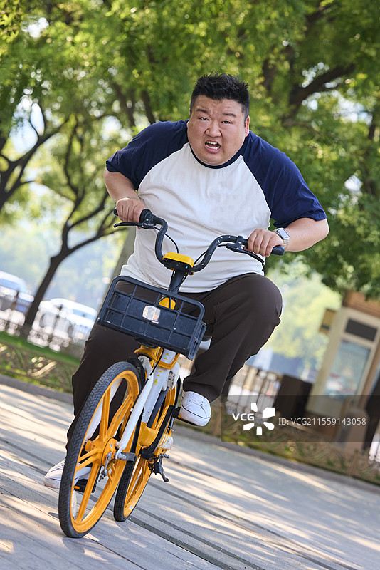 户外骑共享单车的肥胖青年男人图片素材
