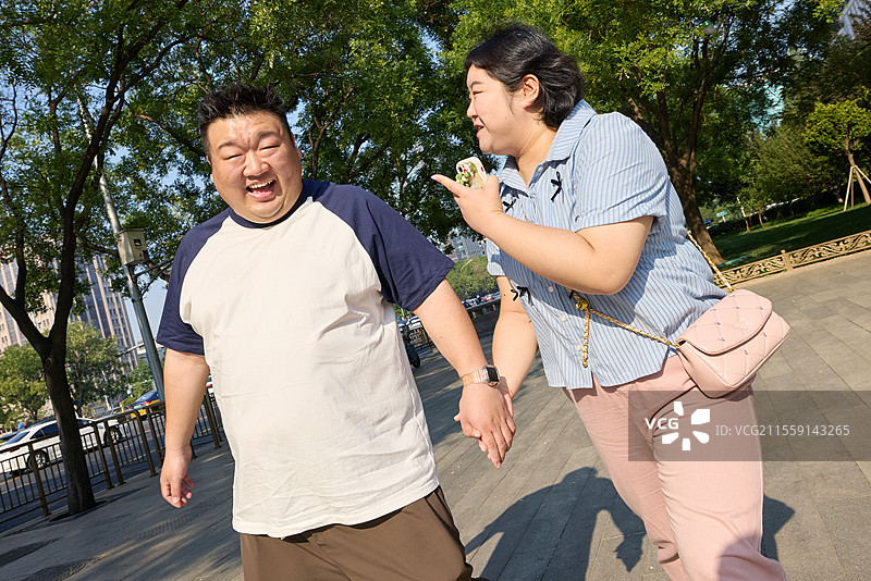 手牵手步行的青年胖子情侣图片素材