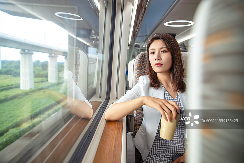 高铁车厢内坐在座位上透过窗户往外看的青年女人图片素材