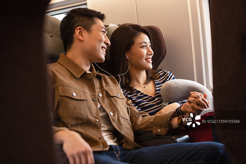 高铁车厢内坐在座位上聊天的青年情侣图片素材