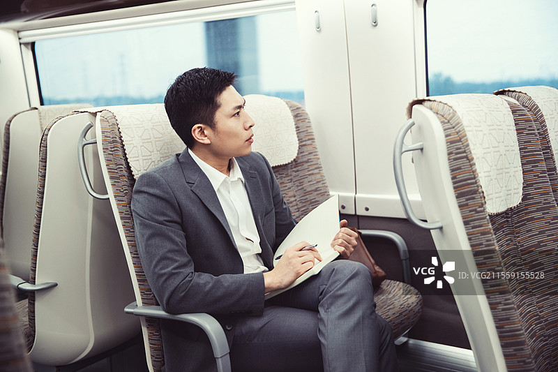 高铁车厢内坐在座位上工作的青年男人图片素材
