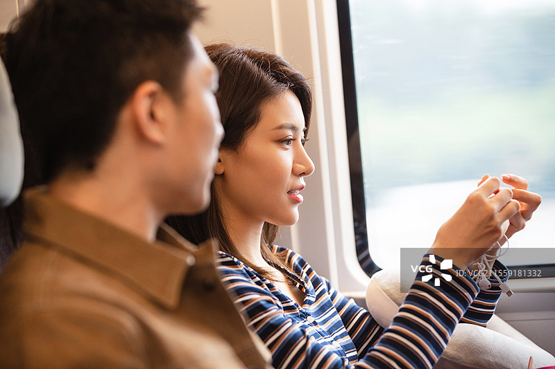 高铁车厢内坐在座位上聊天的青年情侣图片素材