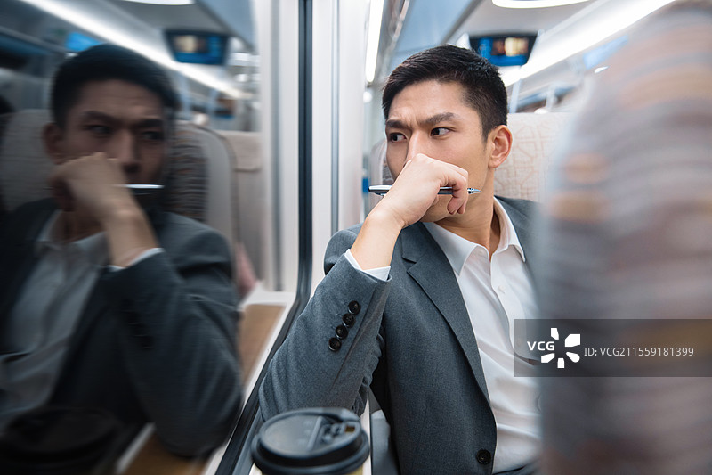 高铁车厢内坐在座位上透过车窗往外看的青年男人图片素材
