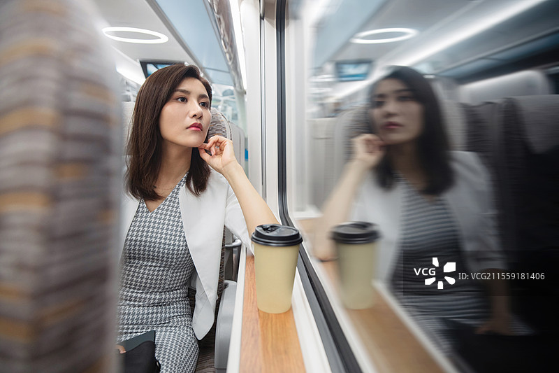 高铁车厢内坐在座位上透过窗户往外看的青年女人图片素材
