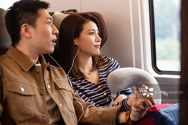 高铁车厢内坐在座位上聊天的青年情侣图片素材