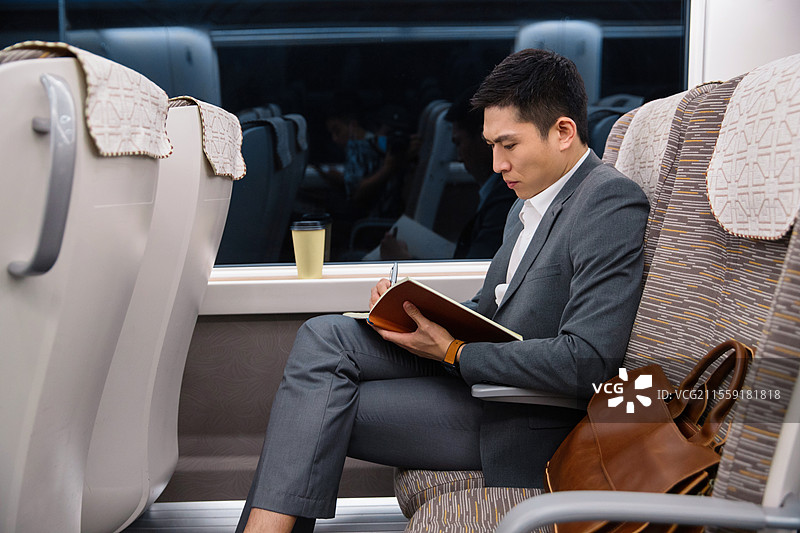 高铁车厢内坐在座位上工作的青年男人图片素材