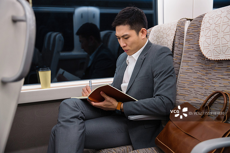 高铁车厢内坐在座位上工作的青年男人图片素材