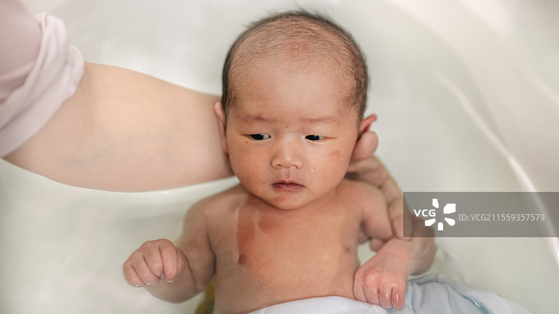 母亲在浴缸里给男婴儿子洗澡的高角度照片图片素材