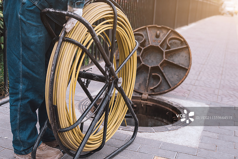 公用事业工人管理露天检修孔附近的黄色电缆图片素材