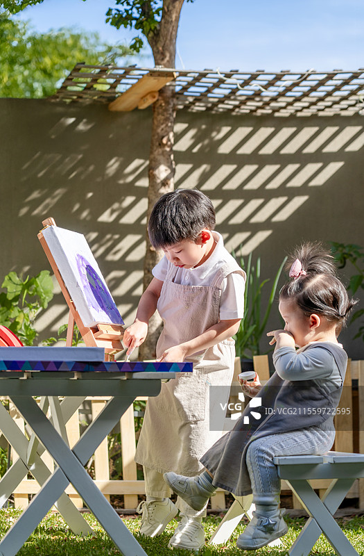 院子里一岁小女孩看小哥哥画画图片素材