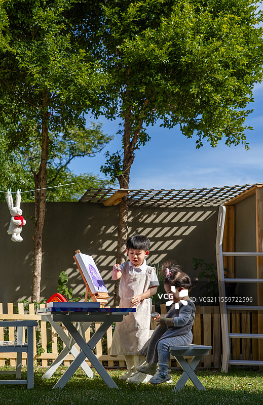 院子里一岁小女孩看小哥哥画画图片素材