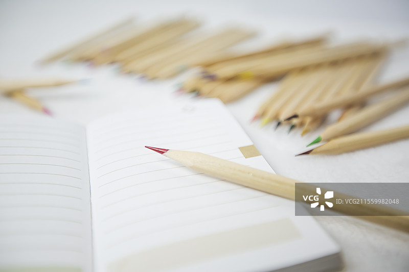 白色桌面上的彩色铅笔和笔记本图片素材