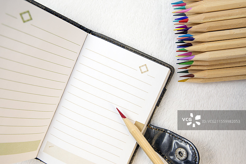 白色桌面上的彩色铅笔和笔记本图片素材