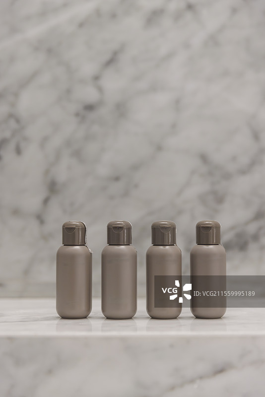 四个棕色小瓶子放在浅白色大理石台面背景上，设计素材留白抠图图片素材