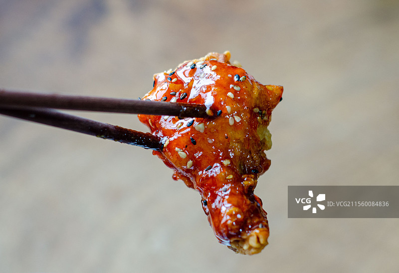 芝麻酱汁包裹的美味琥珀炸鸡块筷子夹着吃图片素材