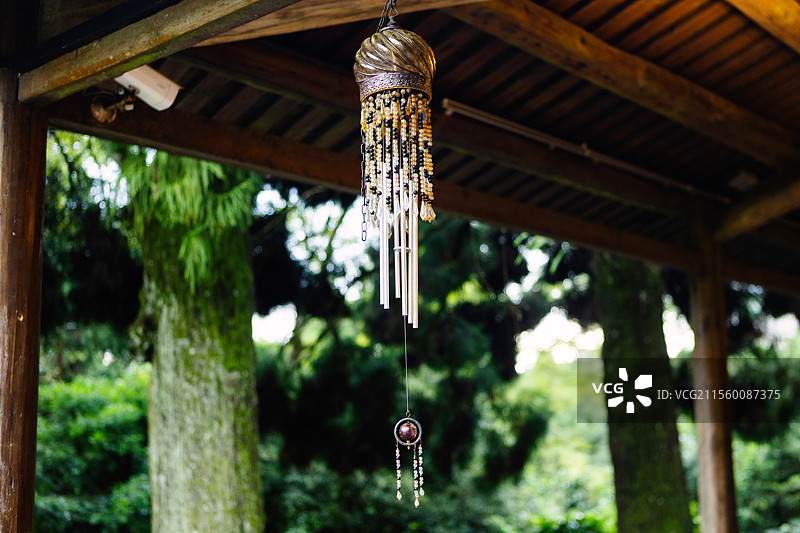 屋檐下悬挂的精致银色风铃随风轻轻摇曳，在传统宁静的环境中唤起一种静谧而诗意的氛围。图片素材