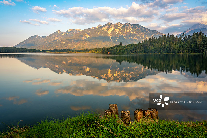 阿尔卑斯山巴姆湖Barmsee湖光山色相映成趣，静谧的湖泊倒映着山脉和天空。阳光穿透云层，洒落在山林图片素材