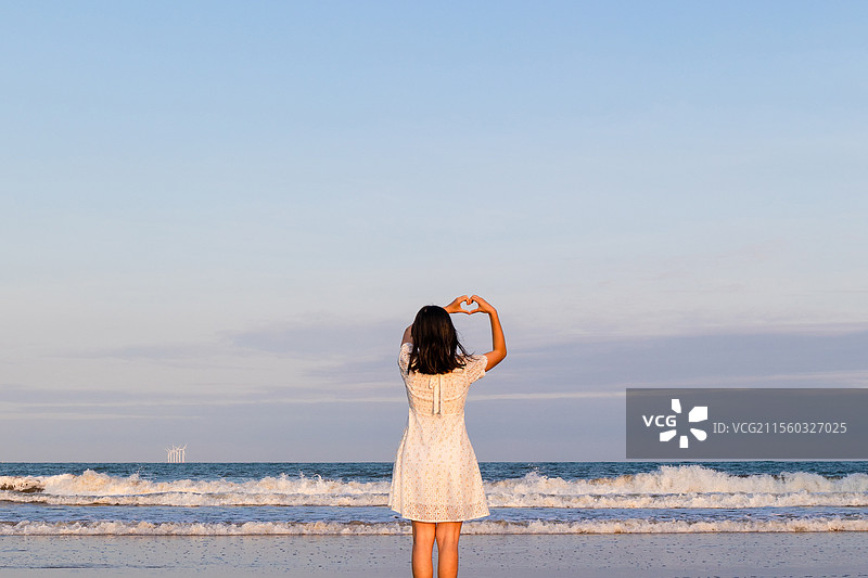 黄昏时分海滩上的一名中国女性背影图片素材