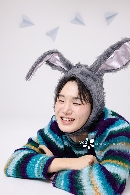 一个戴着兔子帽子的男人摆出顽皮的姿势，仿佛回到了童年。图片素材