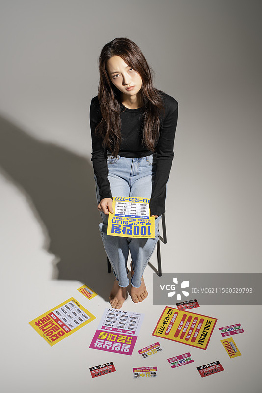 地上散落着贷款宣传单，一位20多岁的年轻人对获得贷款感到无助。图片素材