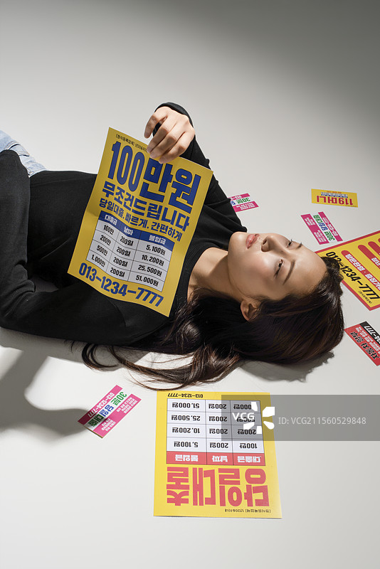 地上散落着贷款宣传单，一位20多岁的年轻人对获得贷款感到无助。图片素材