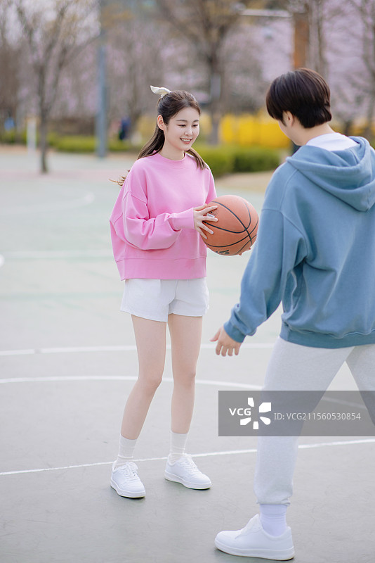 一对年轻情侣在公园享受篮球约会图片素材