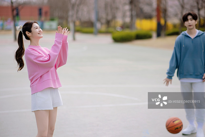 一对年轻情侣在公园享受篮球约会图片素材