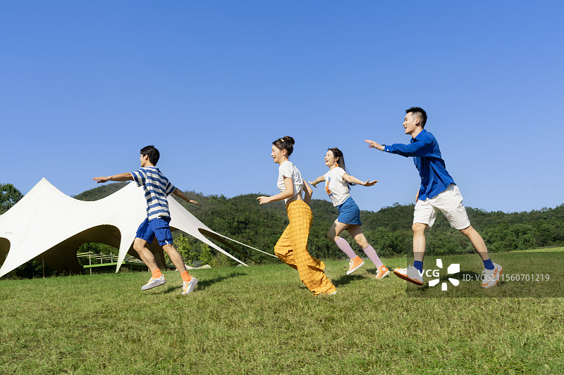 在户外草坪上疯狂追逐奔跑的四个年轻人图片素材