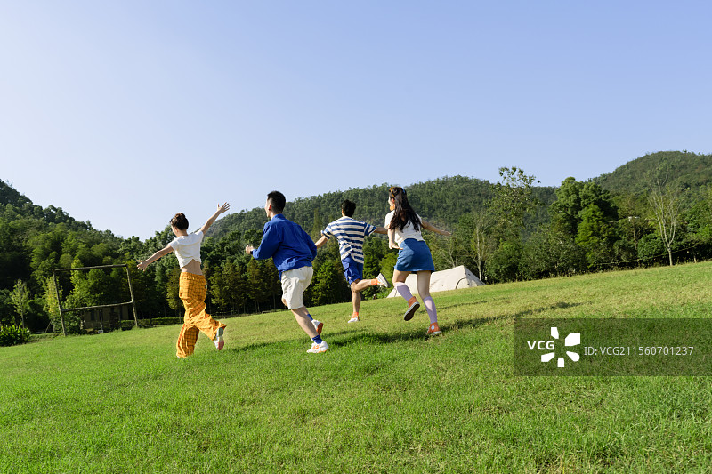在户外草坪上疯狂追逐奔跑的四个年轻人图片素材