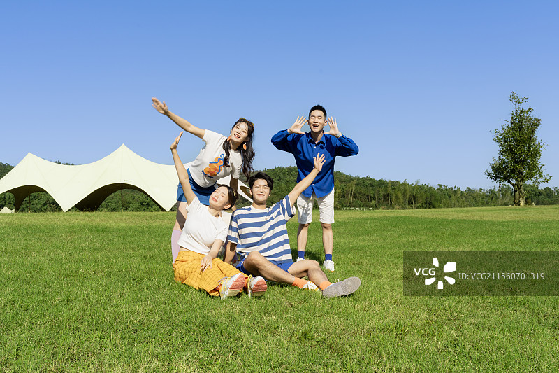 坐在草坪上拍摄合影的四个年轻人图片素材