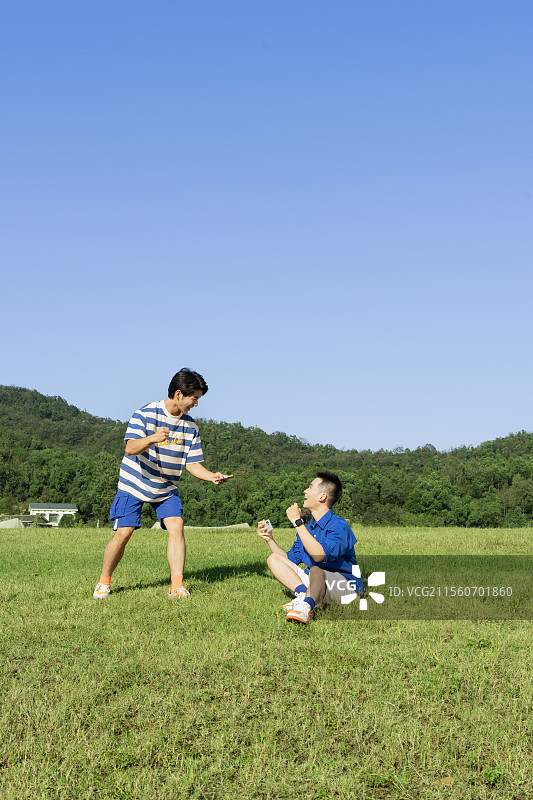坐在草坪上玩手机游戏的两个年轻男子图片素材