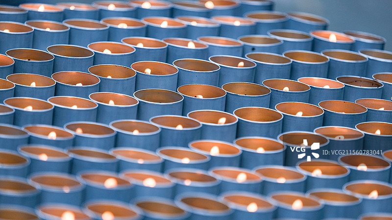 寺庙里祈福的堆叠金属蜡烛燃烧的全帧照片大光圈壁纸背景图图片素材