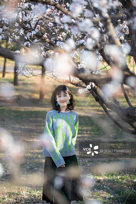 年轻美丽的女孩在花园里玩，春天樱花盛开的美丽少女图片素材