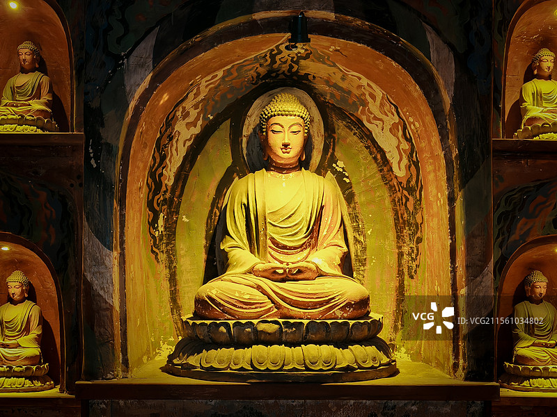 照片展示一尊端坐于拱形龛内的佛像，佛像姿态庄严，周围壁龛中还有其他佛像，整体氛围庄严肃穆。图片素材