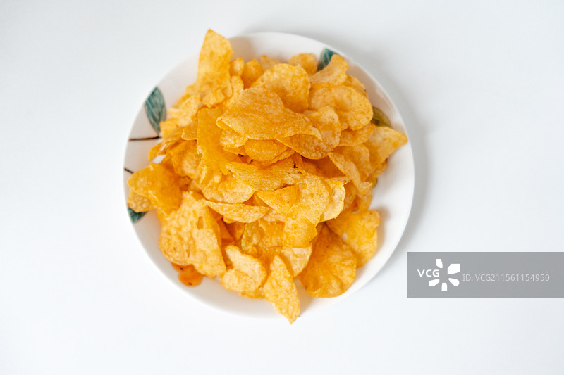 一盘白色彩绘碟子里装着一堆膨化薯片零食图片素材