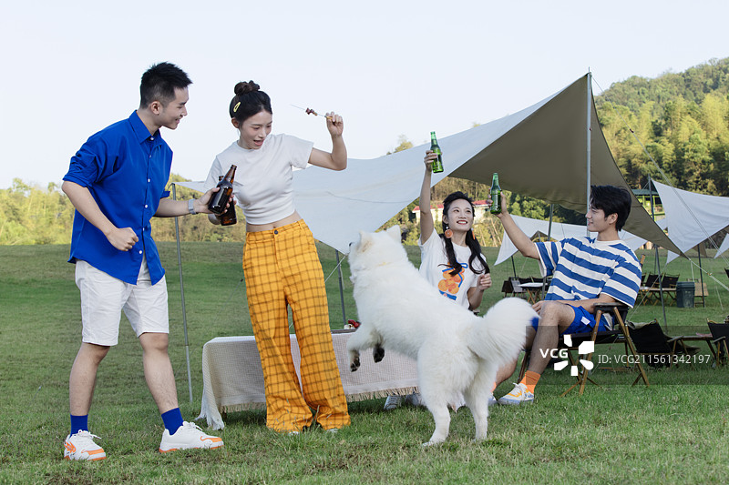 四个年轻人与宠物狗一起吃烧烤图片素材