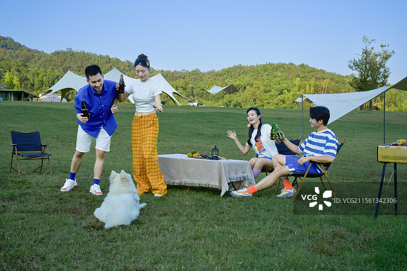 四个年轻人与宠物狗一起吃烧烤图片素材