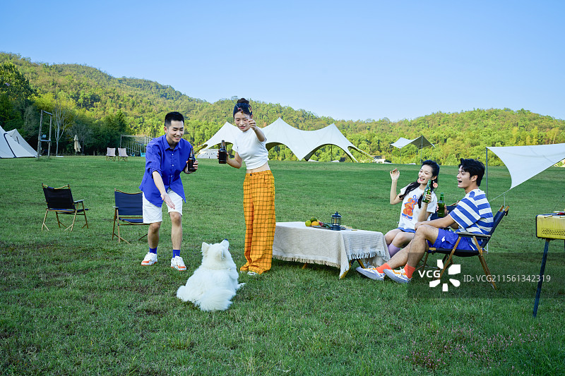 四个年轻人与宠物狗一起吃烧烤图片素材