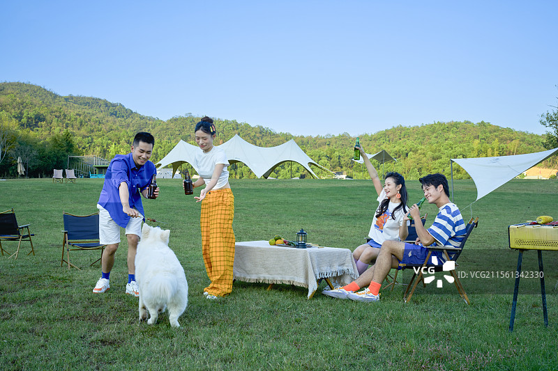 四个年轻人与宠物狗一起吃烧烤图片素材