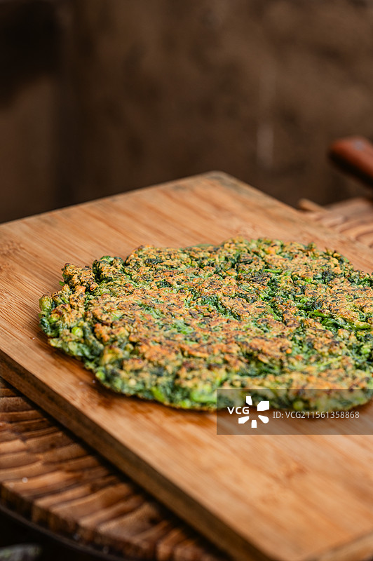 木砧板上金黄酥脆的绿色蔬菜煎饼，散发质朴香气，展现家常面，适合健康食谱或田园风格美食摄影图片素材