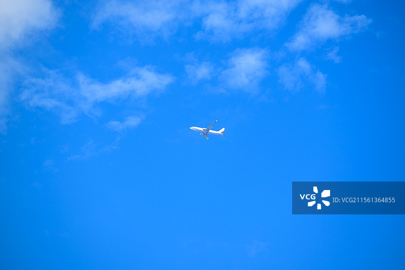 晴朗春日的蓝天白云下飞机穿云而过的地角度视图图片素材