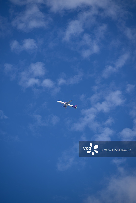 晴朗春日的蓝天白云下飞机穿云而过的地角度视图图片素材