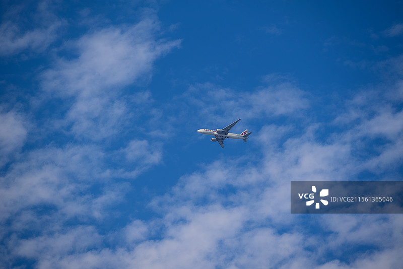 晴朗春日的蓝天白云下飞机穿云而过的地角度视图图片素材
