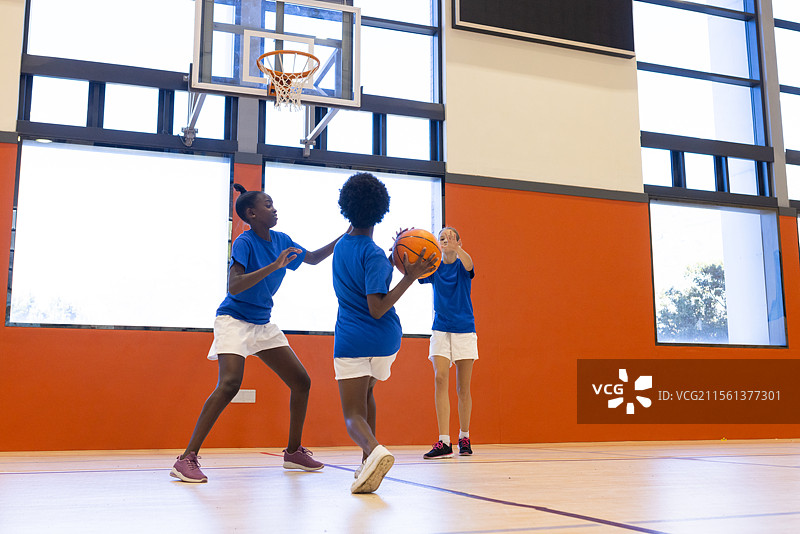 在学校体育馆打篮球，多元化的女孩们一起练习并享受乐趣图片素材