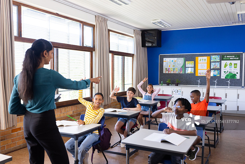 在教室里，学生们举手回答老师的问题图片素材