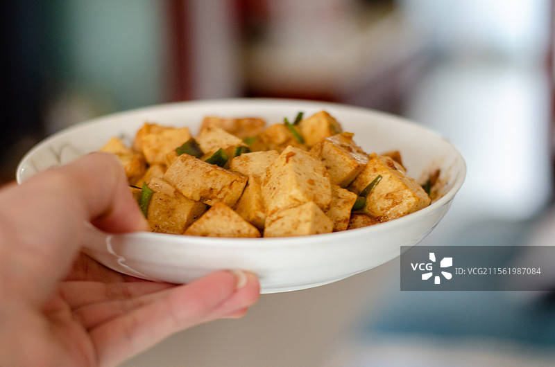 手持装有调味豆腐的白碗图片素材