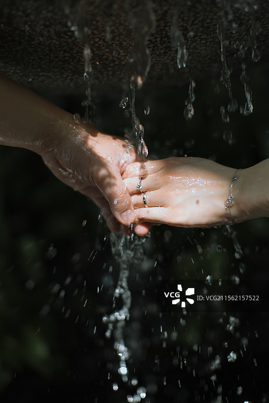 情侣在流水瀑布中牵手图片素材